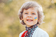 Smiling Little Ukrainian Boy With Blue Yellow Flag Art On Cheek. Child In Traditional Embroidery Vyshyvanka Shirt. Ukraine, Freedom, National Costume, Victory In War.