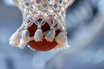 Wall Mural - The orange basketball ball flies through the basket. Professional sport concept..