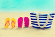 Summer vacation concept - bag and flip flops on the beach on blue sea background