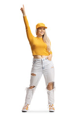 Wall Mural - Full length portrait of a happy young female with a cap pointing up