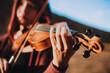 Detalle de Mujer joven tocando violín en una montaña al atardecer. Concepto de personas y música.
