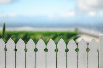 Close up image of white picket fence with beautiful beach scenery out of focus in background providing copy space