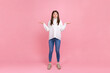 Full length portrait of helpless pretty female with spread arms, does not know answer on questions, wearing white casual style sweater. Indoor studio shot isolated on pink background.