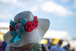 An attendee at a horse race, wearing a fancy hat.
