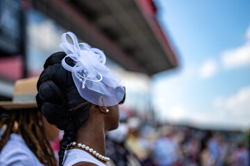 An attendee at a horse race, wearing a fancy hat.