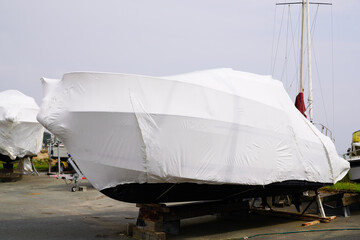 Wall Mural - boat out of water protected by a plastic film for wintering ship under tarpaulin tarp