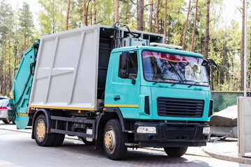 Fototapete - A garbage truck picks up garbage in a residential area. Loading mussar in containers into the car. Separate collection and disposal of garbage. Garbage collection vehicle.