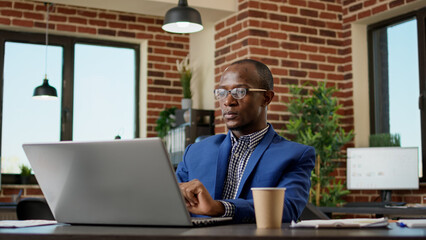 Wall Mural - Company employee writing business report on laptop, typing research information on internet browser. Office worker using statistics to plan project presentation on computer app.