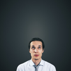 Poster - Man looking up in white shirt and tie isolated on blank dark grey background with empty space for your text or logo, mockup. Thinking and brainstorming concept, close up