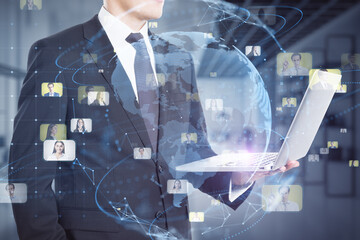 Poster - businessman hands using laptop with creative glowing blue globe hologram with faces on blurry office interior background. Hire, alumni, online conference and search concept. Double exposure.