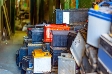 Discarded old car batteries in a garage for recycling in a lead scrap yard. Selective focus.