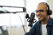 © Chanakon - Content creator asia man host streaming his a podcast on laptop with headphones and condenser microphone interview guest conversation at home broadcast studio. Male blogger recording voice over radio