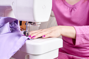 Wall Mural - Woman sewing a dress on a sewing machine. Close-up, selective focus