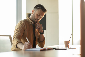 Poster - Thoughtful Businessman Writing Taking Notes Using Laptop At Workplace