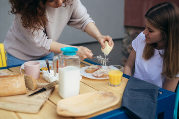 mother and daughter breakfast together at home in backyard