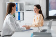 © Syda Productions - medicine, healthcare and people concept - female doctor with clipboard talking to smiling woman patient at hospital