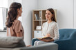 psychology, mental health and people concept - smiling psychologist with notebook and woman patient at psychotherapy session