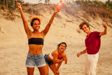 Multinational Friends Dancing And Singing With Spark Stick On Ste Sandy Beach.usa Independence Day Concept