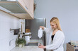 © makedonski2015 - A young woman pours clean water into a glass in a bright and clean kitchen
