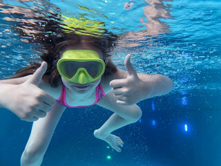 Smiling child in goggles swim, dive in the pool with fun - jump deep down underwater. Healthy lifestyle, people water sport activity on summers. 