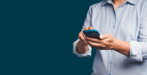 Wall Mural - close-up of hands using a mobile phone while standing over a blue background