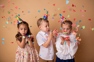 Happy birthday children girls and boy with confetti on beige background