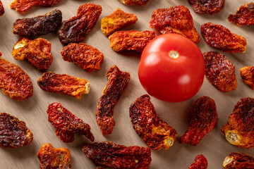 Fresh tomatoes and sun dried tomatoes together on wooden background
