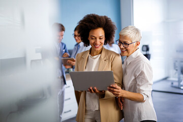 Sticker - Happy multiethnic business women working together online on a laptop in corporate office.