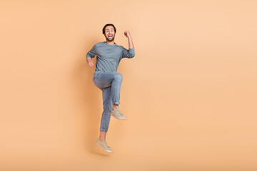 Sticker - Full body photo of young excited man jump celebrate luck triumph fists hands isolated over beige color background