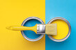 Can of yellow paint with brush on yellow and blue background. Top view, repair concept.
