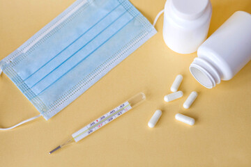 Thermometer, pills and mask on the table. Treatment of flu and colds