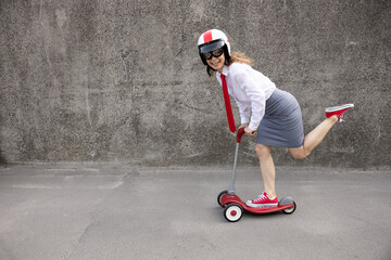 Poster - Funny businesswoman riding scooter outdoor