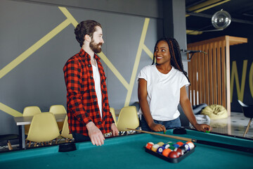 International couple playing a billiard in a club