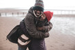 © Caia Image - Happy playful couple hugging on wet winter beach