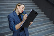 © Andrii  - Busy business woman talking on the phone writing something on the clipboard