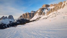 First-person view FPV first-person point of view POV of alpine skiing in Dolomites. Ski resort piste with people skiing in Dolomites in Italy. Ski area Belvedere. Canazei, Italy