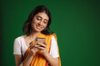 Young indian woman wearing sari smiling and using mobile phone