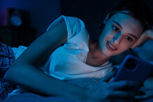 White Girl Using Mobile Phone While Resting On Bed