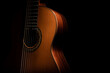 Classical guitar close up, dramatically lit on a black background with copy space.