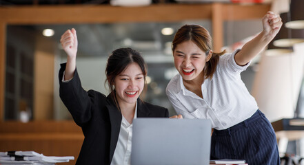 Euphoric winner watching a laptop on a desk winning at working in an office, Asian Teamwork, coworker cooperation, financial marketing team, or corporate business employee concept.