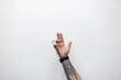 © alones - The male tattoo hand of a professional barber is holding scissors against a white background. barber shop and haircuts, creative concept