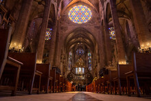 Mallorca, Spain. April 27, 2022. Low Angle View Of Stained Glass Ceiling And Pews In Medieval La Seu Cathedral. Tourists Praying At Beautiful Gothic Church. Interior Of Historic Religious Place.