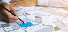 Man Holding A Pencil Pointing To Cadastral Map To Decide To Buy Land. Real Estate Concept With Vacant Land For Building Construction And Housing Subdivision For Sale, Rent, Buy, Investment