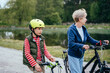 © Iryna - Different generation family communication concept. Smiling senior woman with her grandson walking on a country lane with bicycles with lake on background.