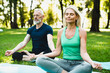 © InsideCreativeHouse - Zen-like lifestyle. Two mature people meditating in lotus position on fitness mats in public park together. Mature couple doing workout outdoors.