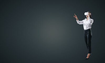 Aufkleber - Woman full length standing and working in virtual reality environment in VR glasses, presses by her finger on virtual interface on black backdrop. Innovate and future technology concept, mock up