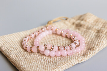 Two bracelets made of natural pink quartz stones beads isolated on gray background. Handmade jewelry. Woman exoteric accessories. Talismans and amulets. Selective focus