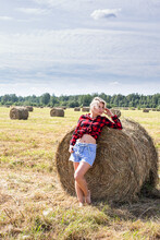 Young Woman Sitting On Hay Bale Summer