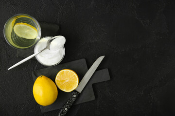 bowl with baking soda, glass of water and lemons on dark background