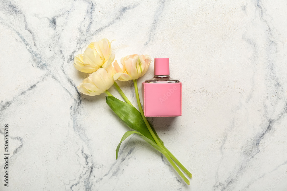 Bouquet of beautiful tulips and perfume bottle on light background